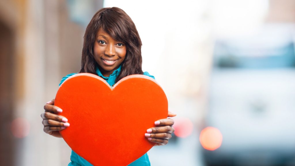 a black woman holding a heart to symbolise love and perfection in her relationship